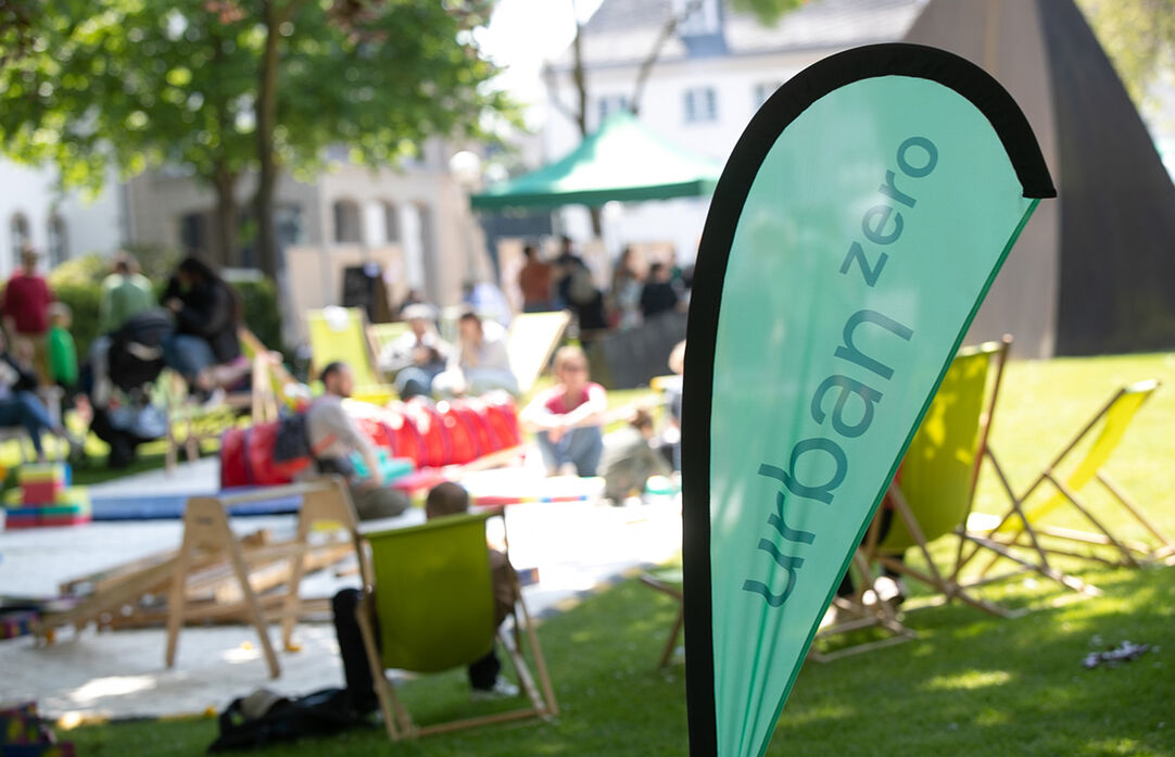 Im Vordergrund steht eine Beachflag. Der Hintergrund ist unscharf. Dennoch erkennt man Menschen und das Festival Gelände.
