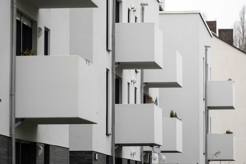 Detailaufnahme von mehreren weißen Wohngebäuden mit auskragenden Balkonen.