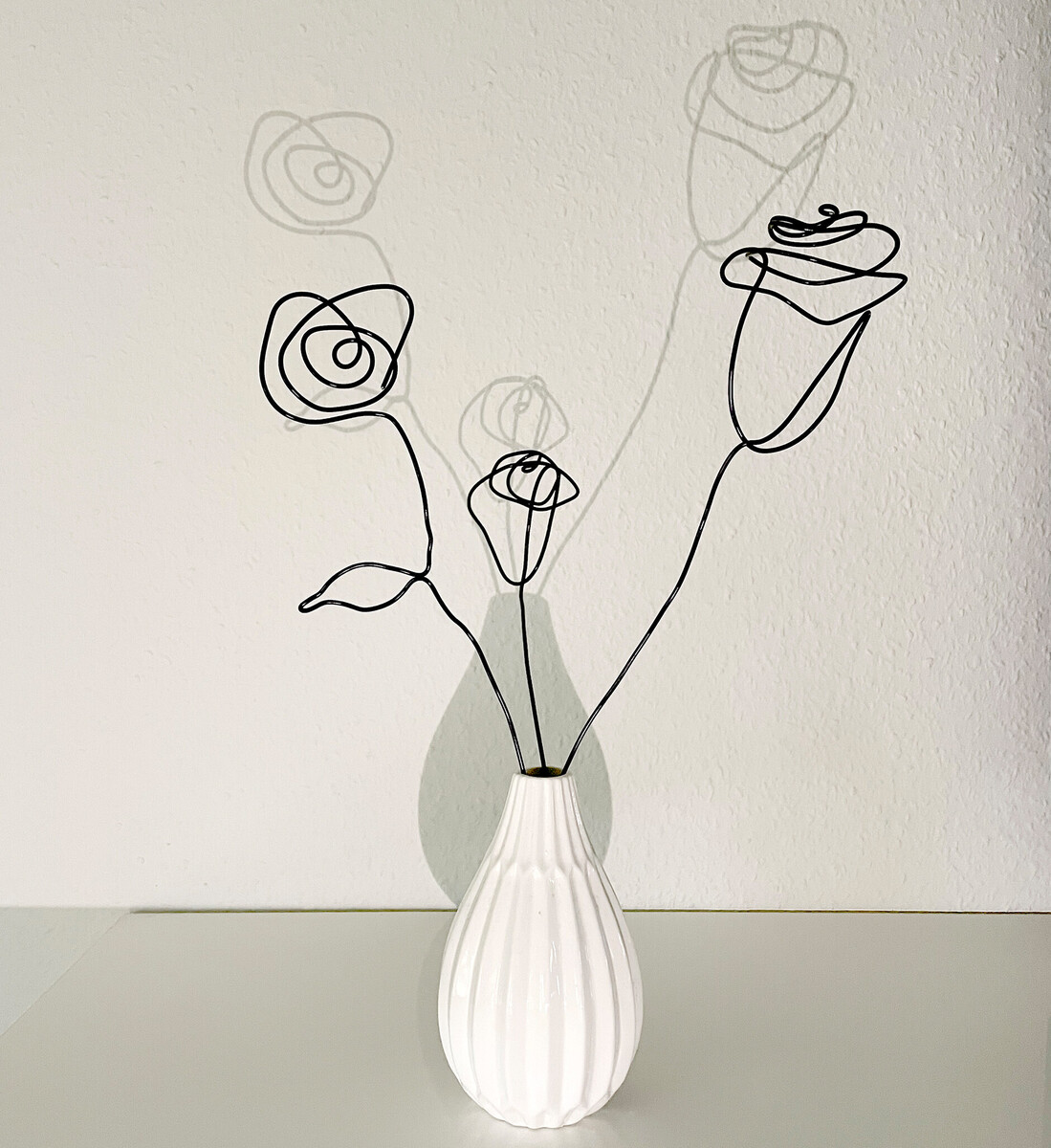 Rosen aus Draht in einer weißen Vase.